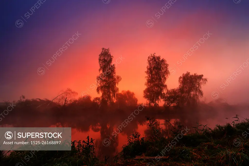 Autumn colorful sunrise on the foggy calm river. Autumn misty morning. Autumn dawn scene panorama.