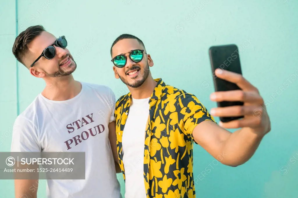 Portrait of happy gay couple spending time together and taking a selfie with mobile phone. Lgbt and love concept.