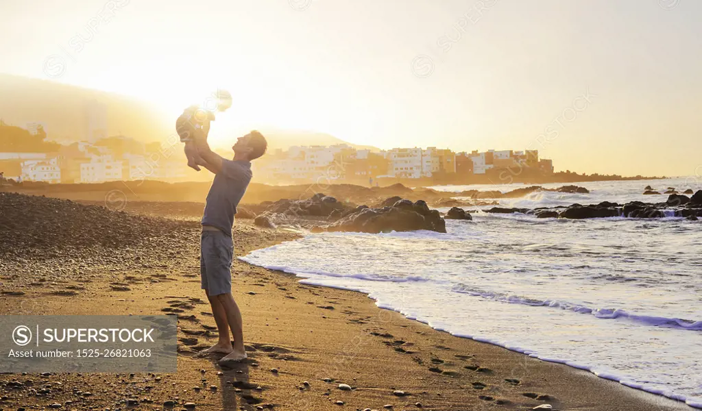 Calm dad posing with baby son over a sunset