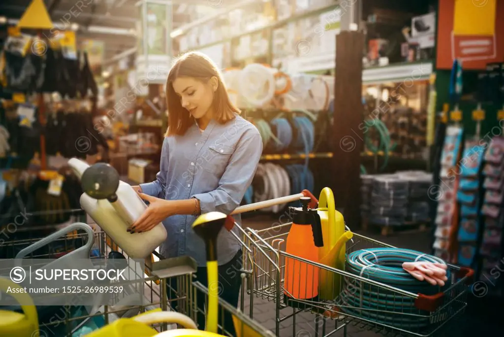 Female buyer choosing gardening tools in shop for gardeners. Woman buying equipment in store for floriculture, florist instrument purchasing. Female buyer choosing tools in shop for gardeners