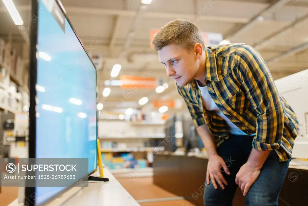 Man choosing TV in electronics store. Male person buying home electrical appliances in market. Man choosing TV in electronics store