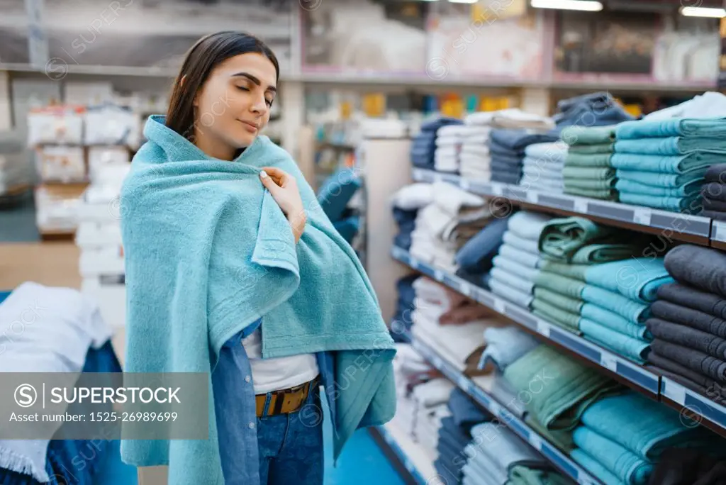 Young woman wrapped herself in a towel, bed linen store. Female person buying home goods in market, lady in bedding shop. Woman wrapped in a towel, bed linen store