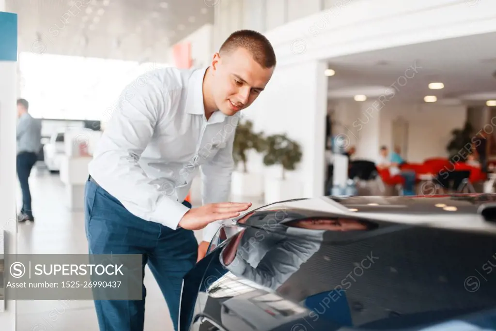 Manager checks the quality of new car paintwork in showroom. Male customer buying vehicle in dealership, automobile sale, auto purchase