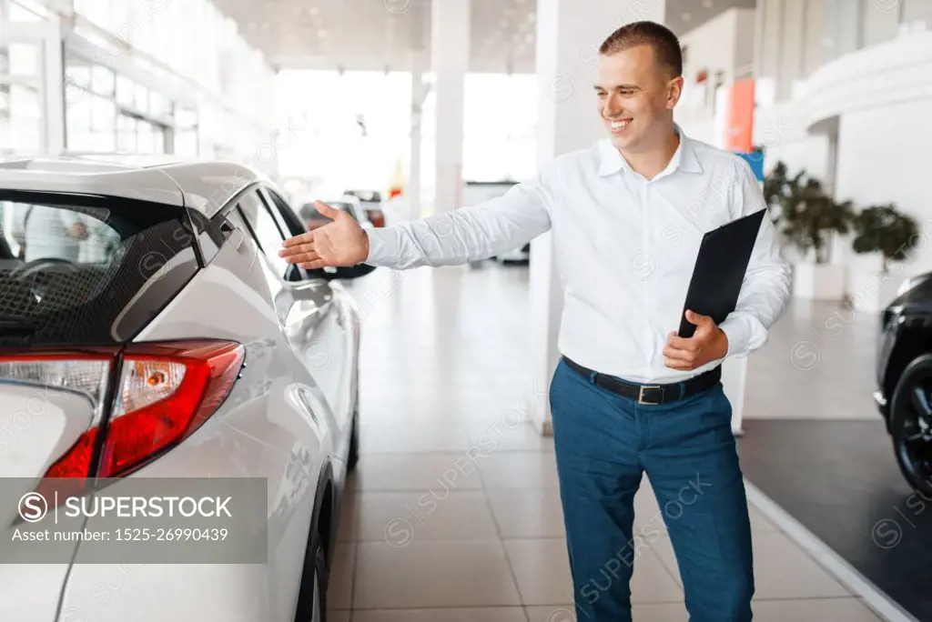 Salesman shows new car in showroom. Male customer buying vehicle in dealership, automobile sale, auto purchase