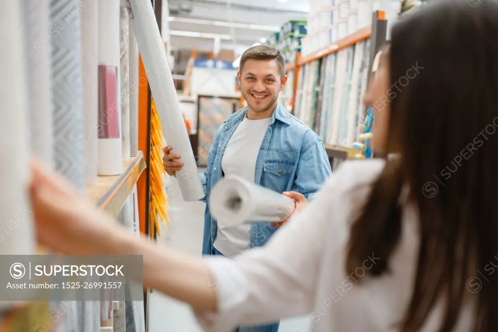 Young couple buying wallcovering in hardware store. Male and female customers look at the goods in diy shop