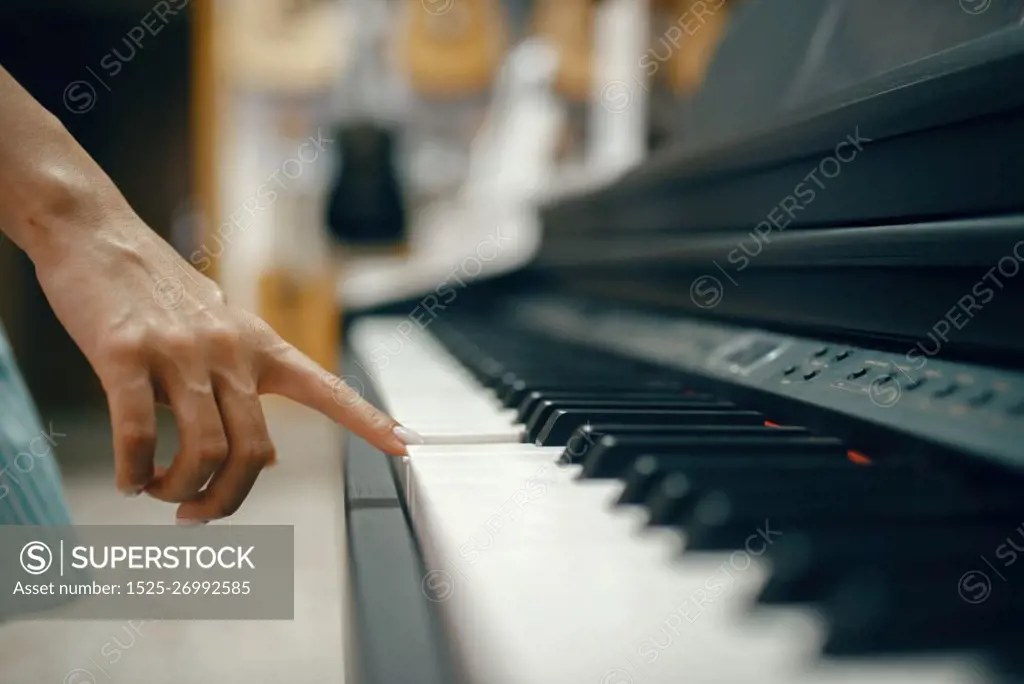 Young woman choosing digital piano in music store. Assortment in musical instrument shop, female musician buying equipment. Young woman choosing digital piano in music store