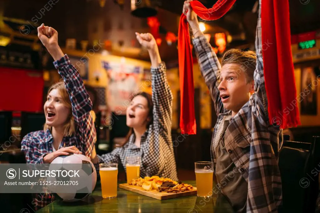 Football fans with scarf watching match and raise their hands up in sports bar. Tv broadcasting, young friends leisures in pub, favorite team wins. Football fans raise their hands up in sports bar