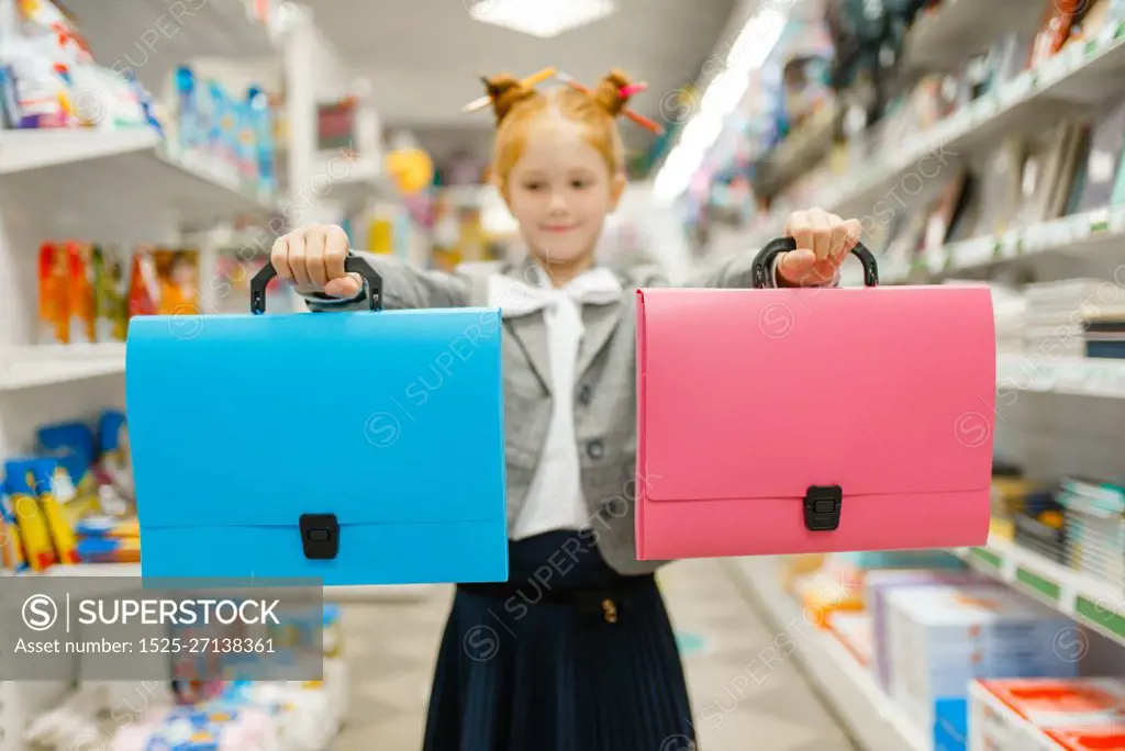 Little school girl with two folders in stationery store. Female child buying office supplies in shop, schoolchild in supermarket