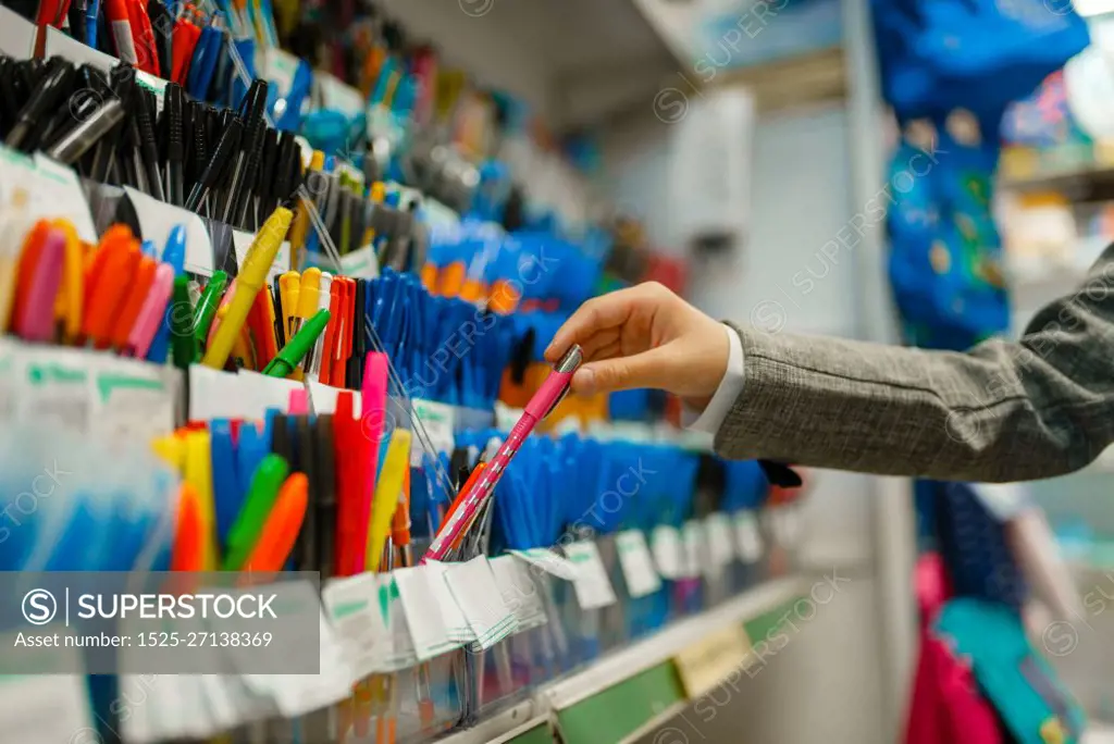 School girl choosing a pen at the shelf in stationery store. Female child buying office supplies in shop, schoolchild in supermarket