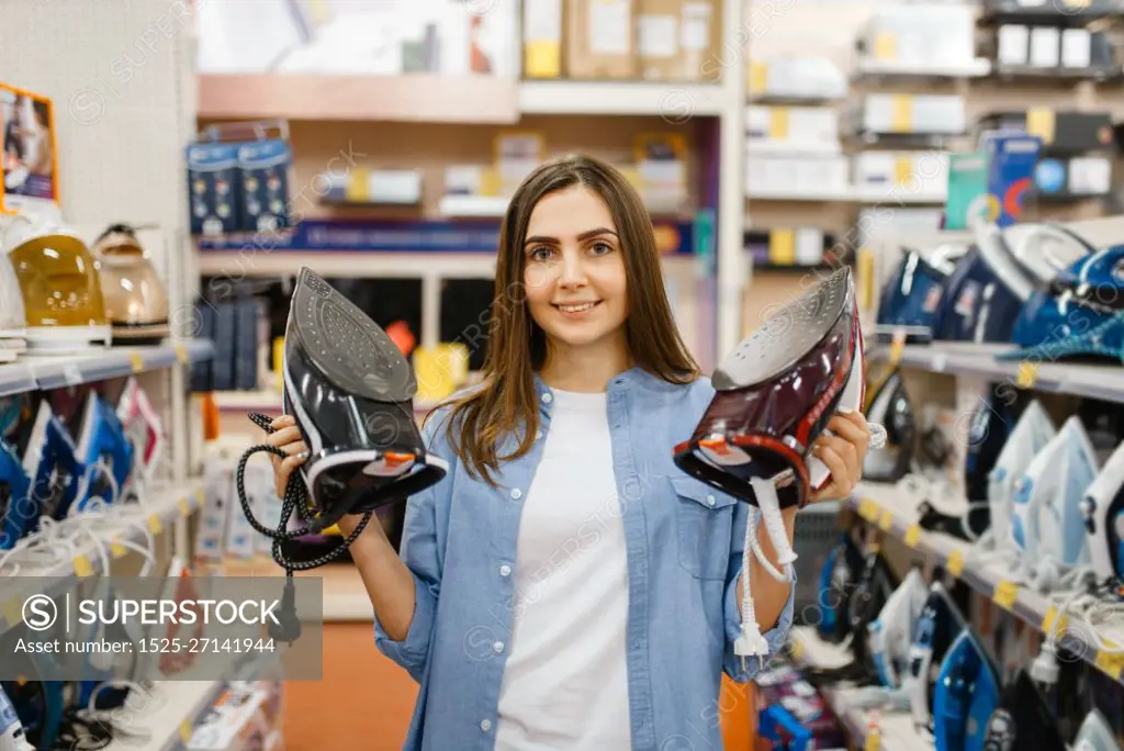 Woman choosing electric iron in electronics store. Female person buying home electrical appliances in market. Woman choosing electric iron in electronics store