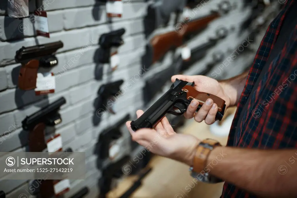 Man holds handgun in gun shop. Male person buying pistol for security in weapon store, selfdefence and sport shooting hobby. Man holds handgun in gun shop