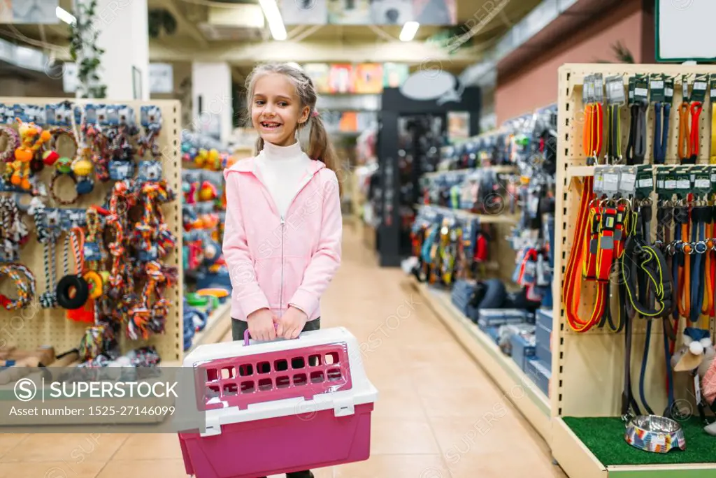 Happy little girl with pink carrier for cat in pet shop. Family buying accessories for kitten in petshop, cat-carrying