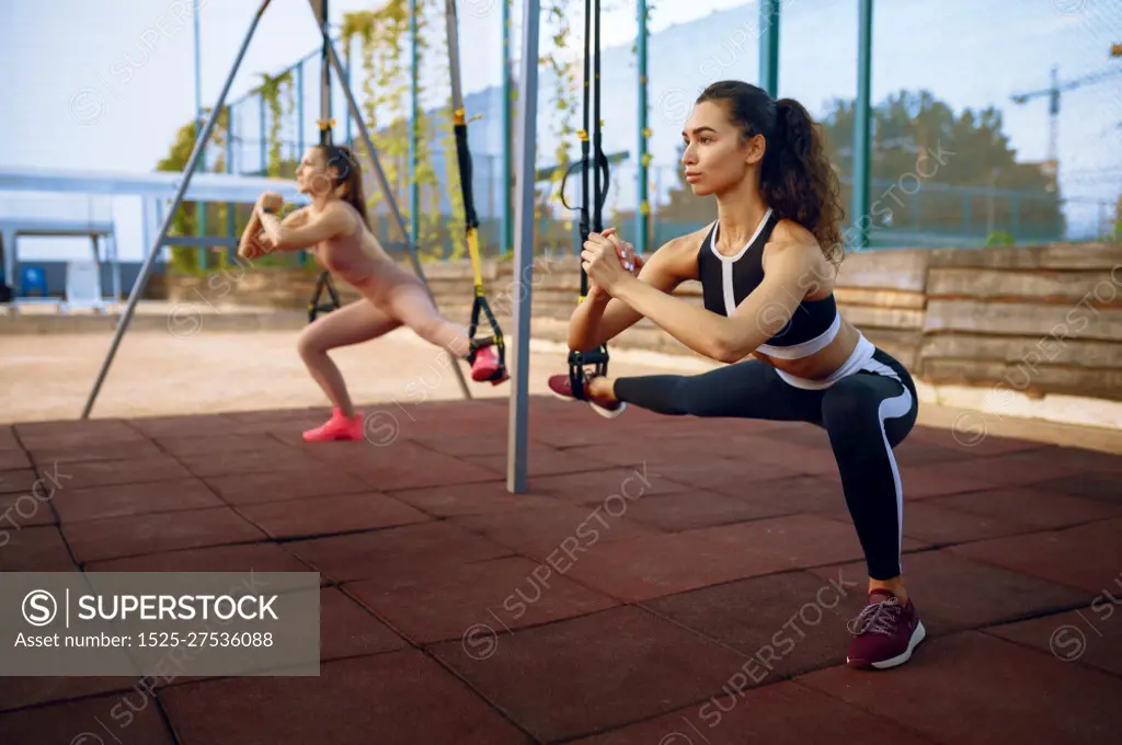 Slim women doing balance exercise on sports ground outdoors, group fitness training. Female athletes in sportswear, team fit workout, teamwork. Slim women doing balance exercise, group training