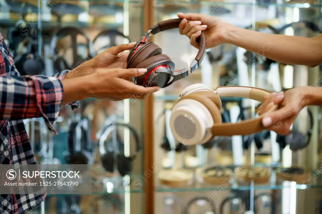 Girl buying headphones in audio store, music fan. Female person in music shop, showcase with earphones on background, buyer in multimedia salon. Girl buying headphones in audio store, music fan