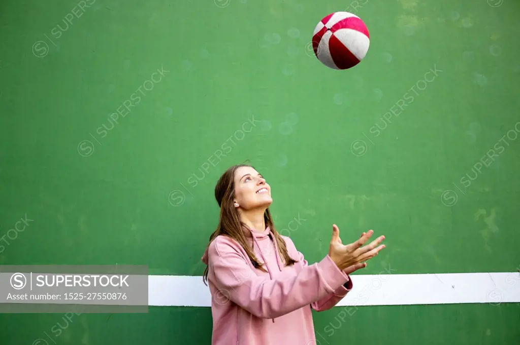 Teenager female playing basketball over green wall