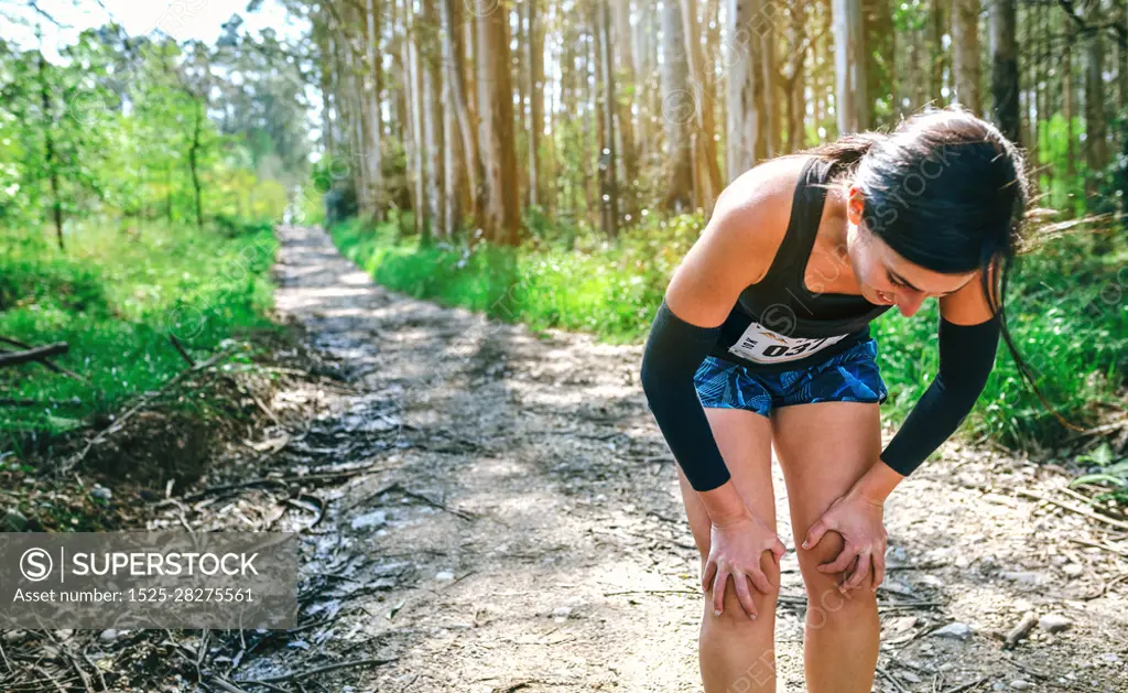 Tired young female athlete pausing at a trail competition. Female athlete pausing at a trail competition