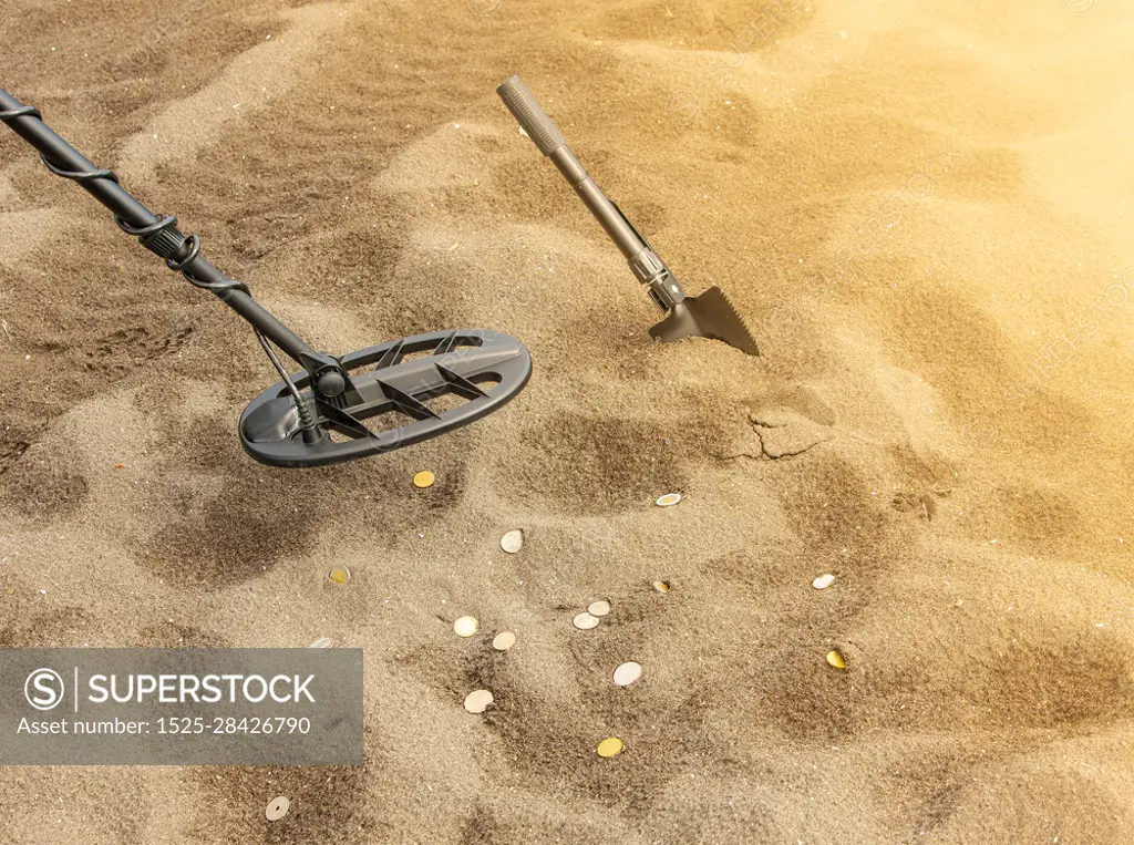 Metal detector, ring and spade on the sand