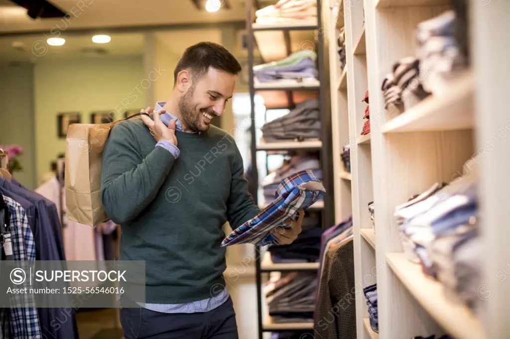 Handsome young man buying shirt in the store