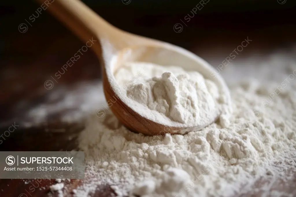 Macro photography of flour with a wooden spoon close-up, light direction, white powder. Macro photography of flour with a wooden spoon close-up, light direction