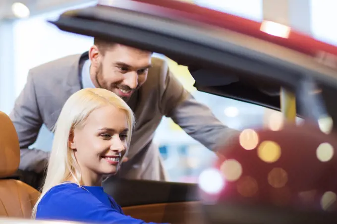 auto business, car sale, consumerism and people concept - happy couple buying car in auto show or salon