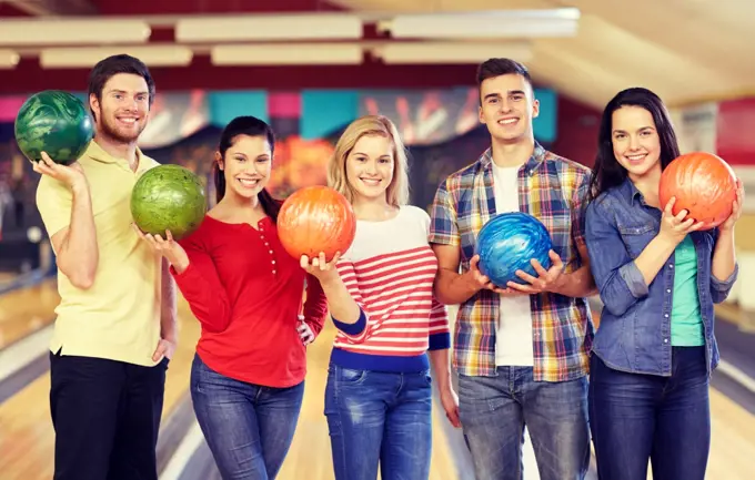 people, leisure, sport, friendship and entertainment concept - happy friends in bowling club