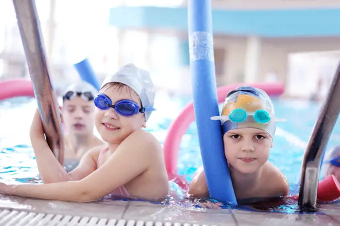 happy children kids group  at swimming pool class  learning to swim