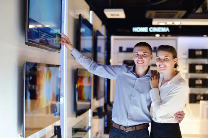 people in consumer electronics  retail store looking at latest laptop, television and photo camera to buy