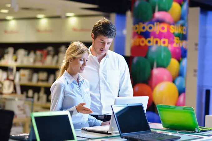 people in consumer electronics  retail store looking at latest laptop, television and photo camera to buy