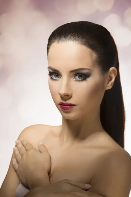 Short portrait of beautiful, young girl with long, straight, brown hair clipped in ponytail, looking in camera on color background&#xA;