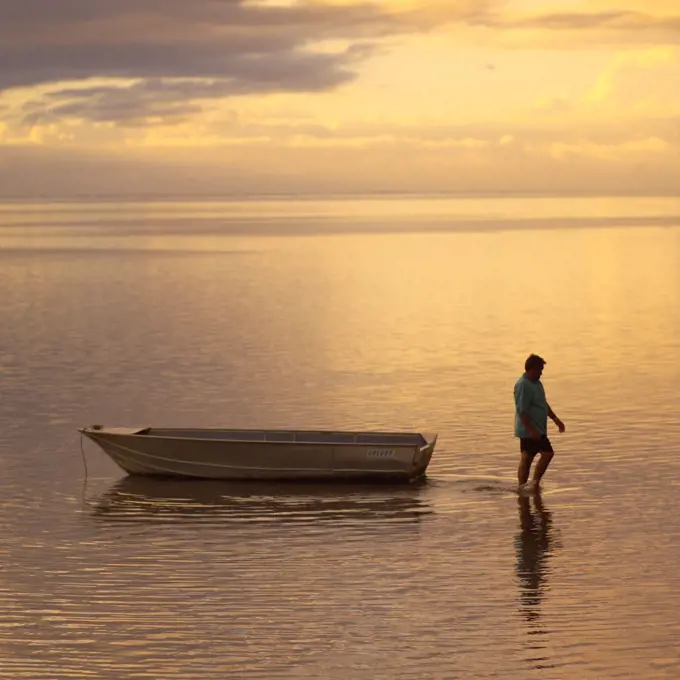 Man walking with boat in ocean at Moorea in Tahiti