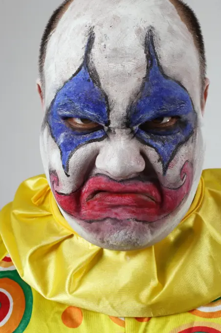 A nasty evil clown, angry and looking mean.