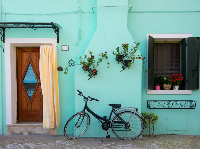 Bicycle near turquoise house on the venetian island Burano, Italy