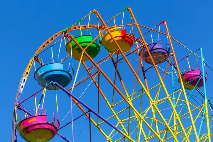 Scenic summer view of color Ferris observation wheel over blue sky in amusement park