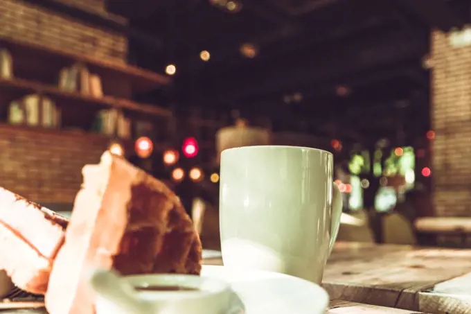 Hot mocha coffee in white cup and blurred waffle on the wooden table