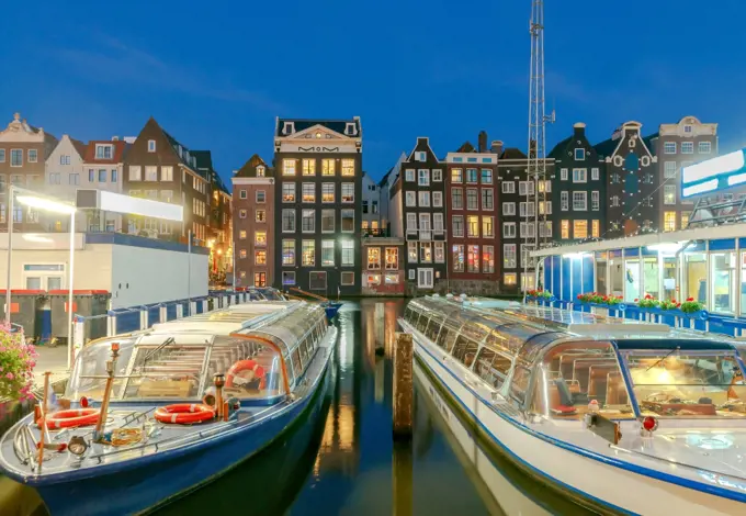 Facades of traditional Dutch houses on the canal in the night light. Amsterdam. Netherlands.. Amsterdam. Night view of the houses along the canal.