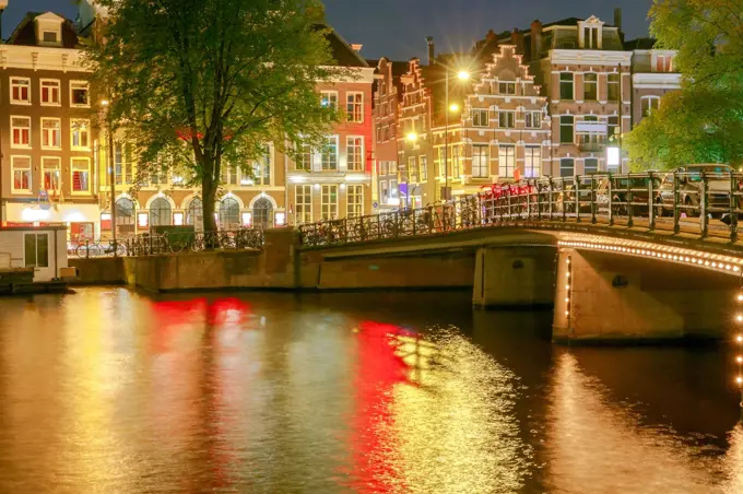 Amsterdam. Night view of the houses along the canal.. Facades of traditional Dutch houses on the canal in the night light. Amsterdam. Netherlands.