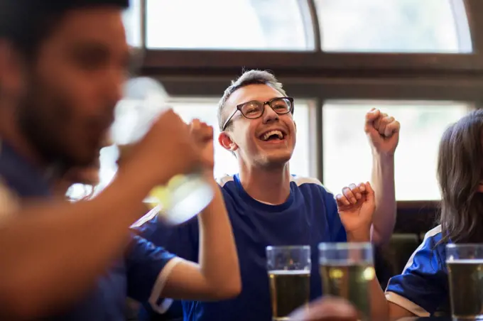 sport, people, leisure, friendship and entertainment concept - happy football fans or friends drinking beer and celebrating victory at bar or pub