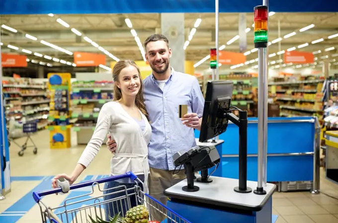 shopping, sale, payment, consumerism and people concept - happy couple with credit card buying food at grocery store or supermarket self-service cash register