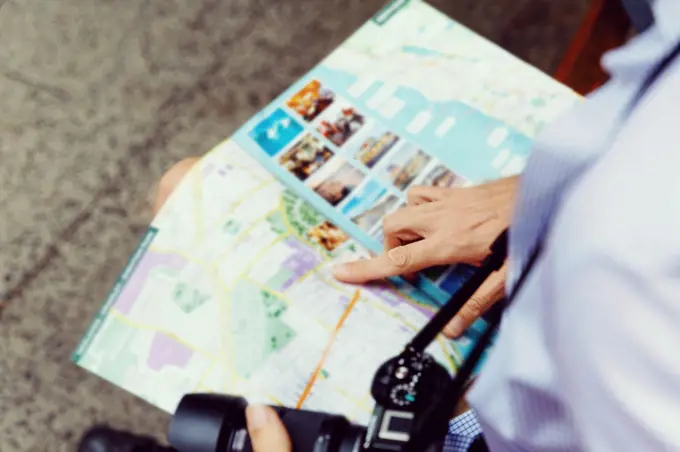 Male tourist in city. Happy male tourist in city with camera and map