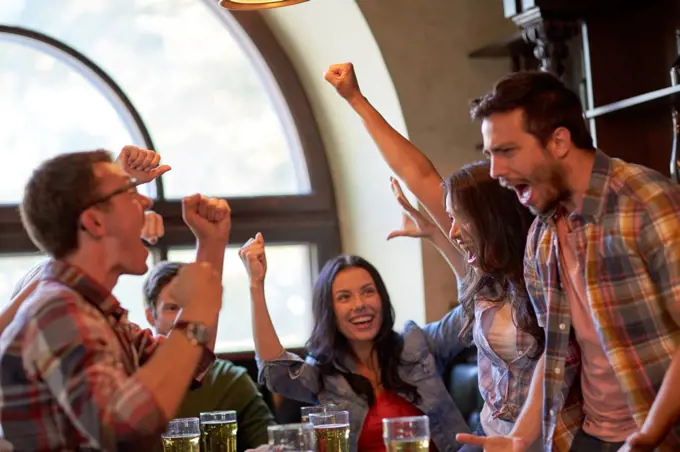 sport, people, leisure, friendship and entertainment concept - happy football fans or friends drinking beer and celebrating victory at bar or pub. football fans or friends with beer at sport bar