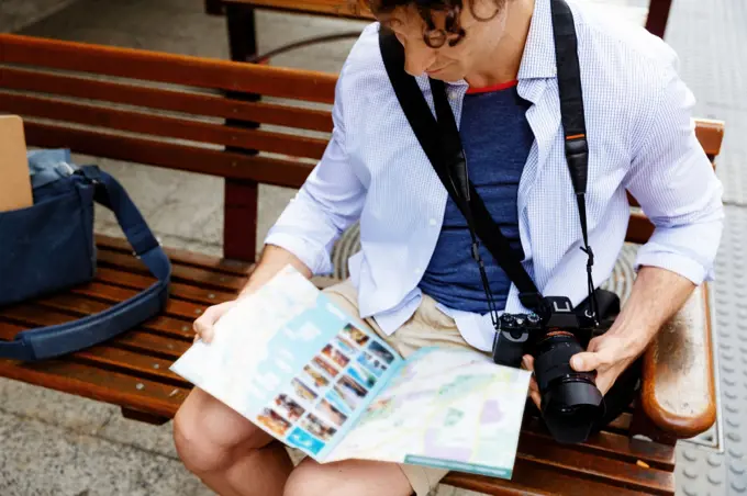 Male tourist in city. Happy male tourist in city with camera and map