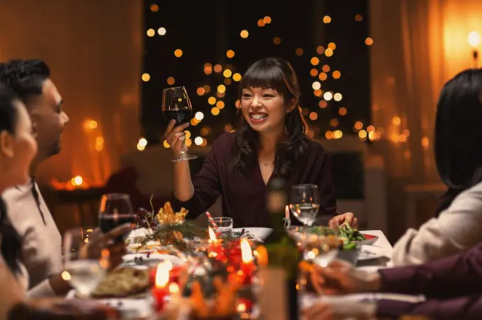 holidays, party and celebration concept - multiethnic group of happy friends having christmas dinner at home and drinking wine. happy friends drinking wine at christmas party