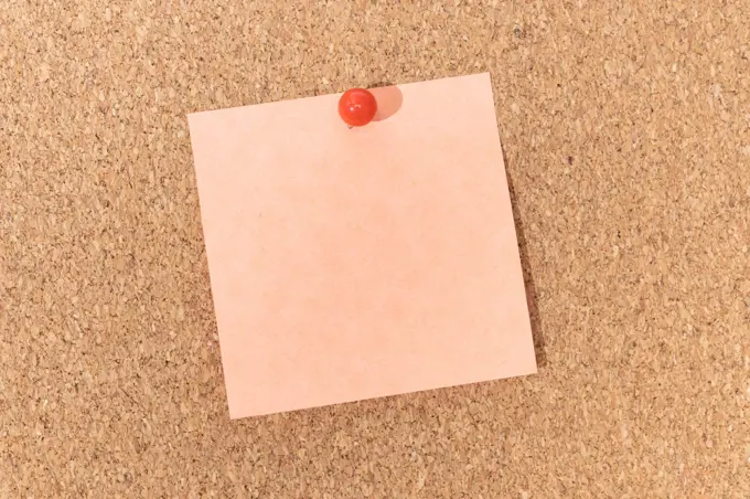 Blank note and push pin on cork board. Template to ad text or drawings