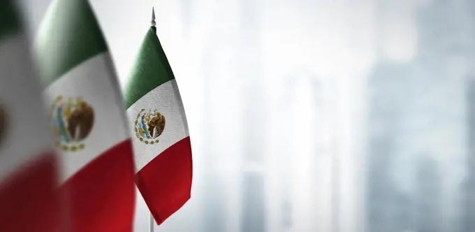 Small flags of Mexico on a blurry background of the city.. Small flags of Mexico on a blurry background of the city