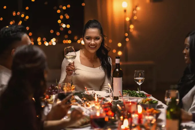 holidays, party and celebration concept - multiethnic group of happy friends having christmas dinner at home and drinking wine. happy friends drinking wine at christmas party