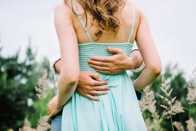 happy guy in a white shirt and a girl in a turquoise dress, the bride and groom are walking in the forest park