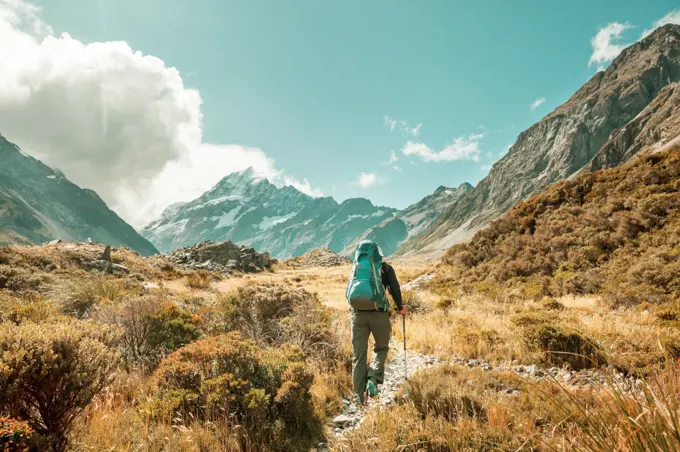 Man walking on hike trail route with Mount Cook National Park, beautiful mountains region. Tramping, hiking, travel in New Zealand.