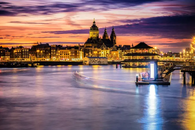 Amsterdam, Netherlands, Holland - December 2019: Pleasure boat on the city&rsquo;s water channels. river IJ. View over the skyline of Amsterdam during sunset 