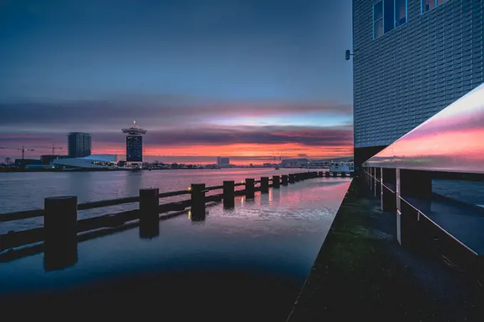 Impressive red cloud sky in the morning above the city of Amsterdam. View over &rsquo;the IJ&rsquo; lake near Amsterdam during the sunrise