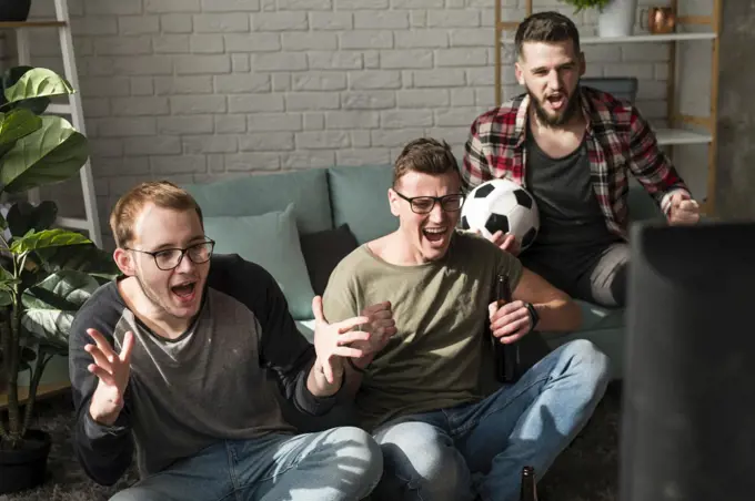 cheerful male friends watching sports tv with football